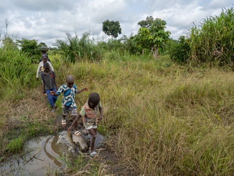 Lailou walks through fields near her Ivory Coast village with three of her grandchildren.