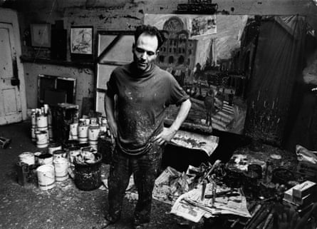 A black and white shot shows a man in his studio surrounded by paints and canvases.