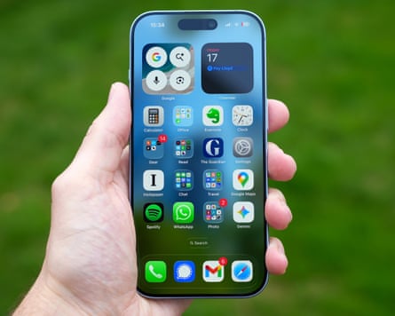 The home screen of the iPhone 17 held outside in a hand.