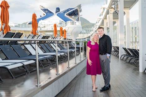 A woman and a man standing with their arms around each other on the deck of a huge ship