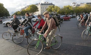 People cycle past the Arc de Triomphe in Paris