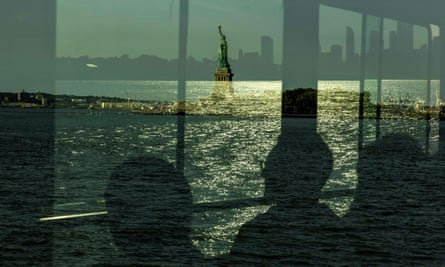 Ghostly shadows of people reflected in a ferry window as they pass the Statue of Liberty on their way to Ellis Island