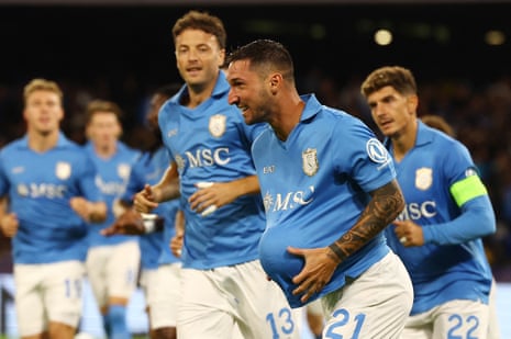 Napoli's Matteo Politano celebrates scoring with the ball under his shirt, running with teammates behind him