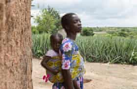 Christy Ansah, 32, with her youngest daughter near the farm in Bentum where she used to work before the land was sold