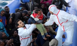 A boy is rescued from a dinghy by Libyan coastguard.