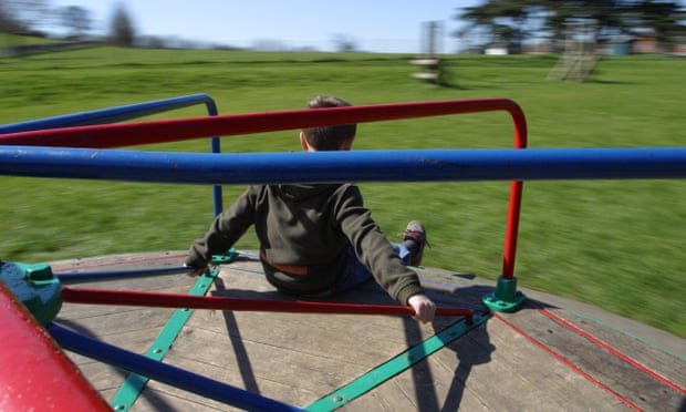 Boy playing on a roundabout in a playground