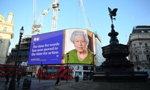 A screen displays an image of Queen Elizabeth II at Piccadilly Circus in London.