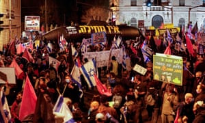 Israelis lift placards and flags as they take part in a demonstration against Prime Minister Benjamin Netanyahu near the PM’s official residence in Jerusalem, amid the coronavirus pandemic crisis, on January 9, 2021.