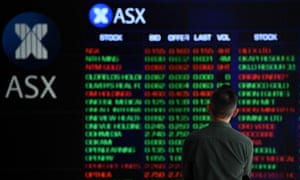 A man stands in front of digital market boards at the Australian Stock Exchange in Sydney, Australia.