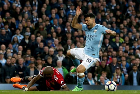Sergio Aguero is floored by Ashley Young in the box.