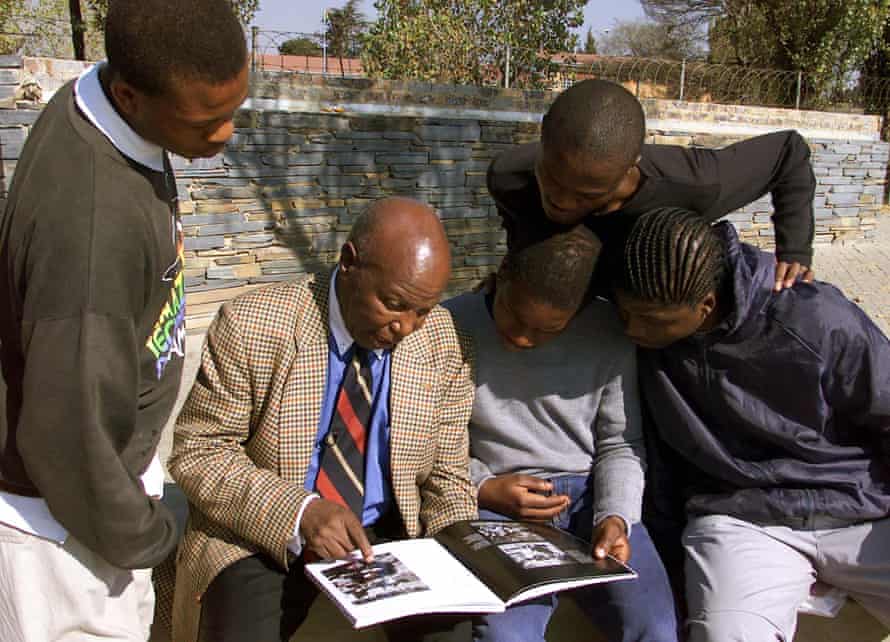 adolescenții privesc în 2001 ca fotoreporter veteran Alf Khumalo, care a murit în 2012, le arată fotografii ale unei clădiri în flăcări lângă școala lor Soweto în timpul revoltei.