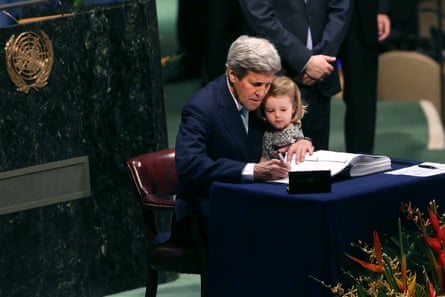 John Kerry, then the US secretary of state, holds his granddaughter while signing the Paris climate accord