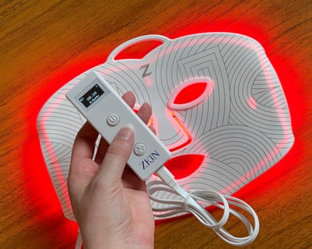 The Zkin mask glowing red with remote held in front of the mask