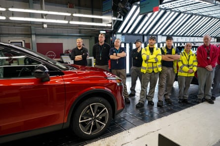 Employees in the Nissan production plant near a red electric vehicle