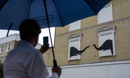 A mural of two elephants in bricked-out windows reaching out their trunks to each other