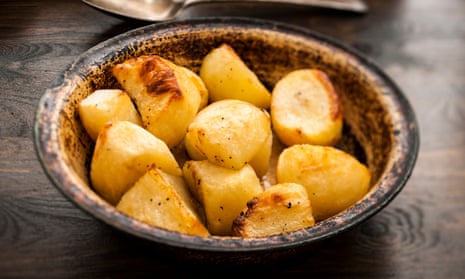 Bowl of roast potatoesRustic metal bowl of roast potatoes on a wooden table.