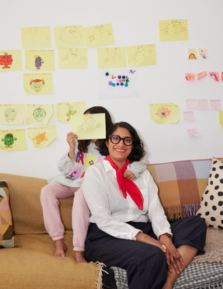 Chitra Ramaswamy with her daughter, sat in front of lots of children’s drawings. Her daughter is holding one