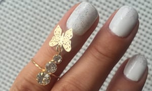 Fingers with rings showing white nail polish on fingernail
