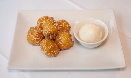 Six boules de banane caramel avec un petit plat sur glace à côté, le tout sur une grande assiette blanche carrée