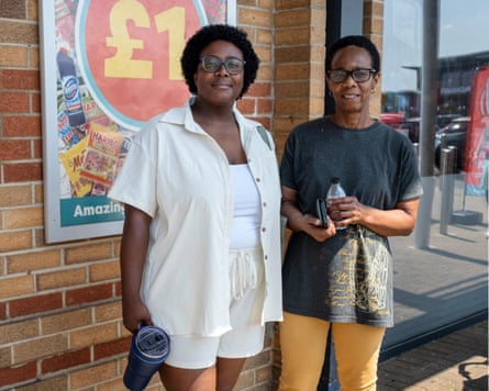 Two shoppers stand in front of Poundland poster