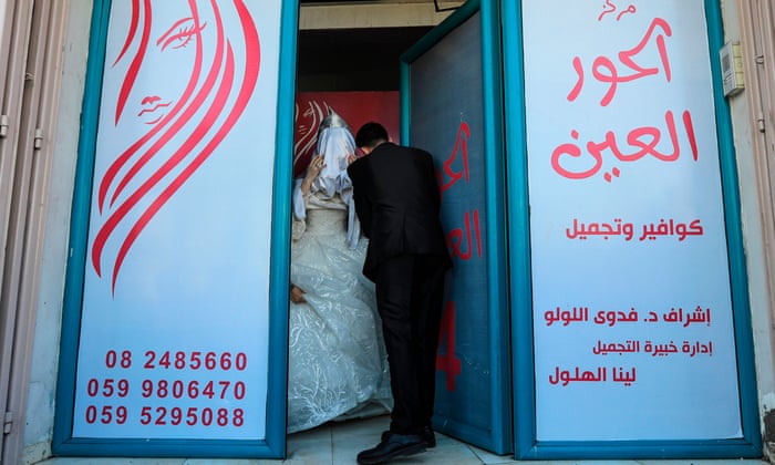 Palestinian groom Ahmed Omar Khallah picks up his veiled bride from a beauty salon in the northern Gaza Strip.