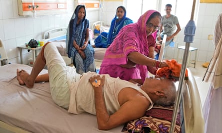 A woman caresses the head of her sick husband at the District Hospital in Palia, Uttar Pradesh, India