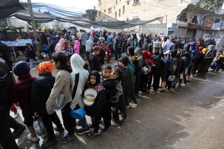 Palestinian children wait in queue for food amid the continuing crisis in Gaza.