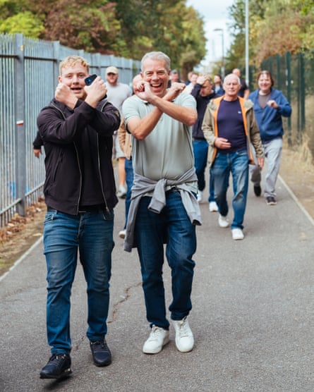 Two men walking down footpath make Hammers signs with arms as they make their way to the stadium