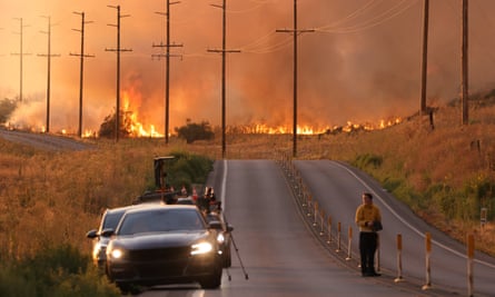A man stands in a road near flames in Moreno Valley in Riverside County, California, on 14 July.