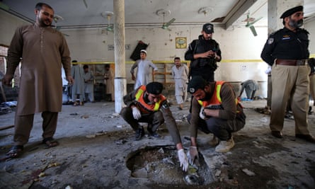 Security officials inspect a crater at the site of the blast at a religious school in Peshawar.