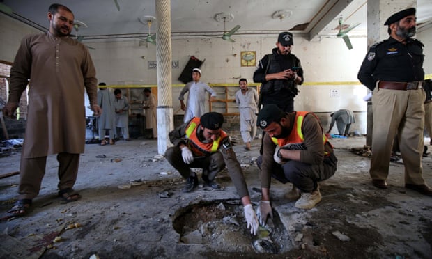 Security officials inspect a crater at the site of the blast at a religious school in Peshawar. 