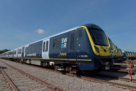 A new South Western Railway train lined up in front of others at a depot.