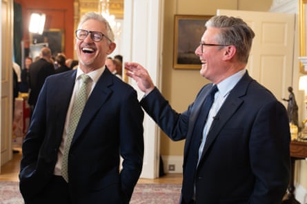 they are standing in a reception room at No 10 Downing Street and both wear suits and ties.