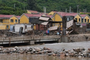 Residents gather near a Shidongzi village signboard on a bridge damaged by the floods.