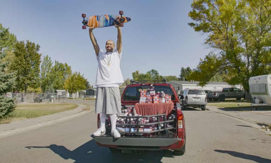 Nathan Apodaca holds his skateboard while standing in the back of a truck containing Ocean Spray products.