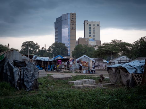 Five-star hotels tower over the IDP camp at the Hai Malakal cemetery in Juba, South Sudan, August 2023. Graves can be seen in the foreground