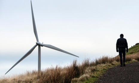 A member of the public walk pasts wind turbines operated by Scottish Power Renewables.