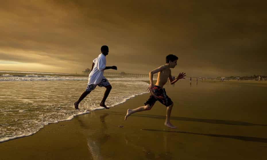 Two boys run near Huntington Beach pier.