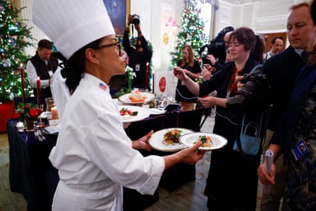 Une chef tient plusieurs assiettes dans ses mains tandis que des membres des médias prennent des photos.