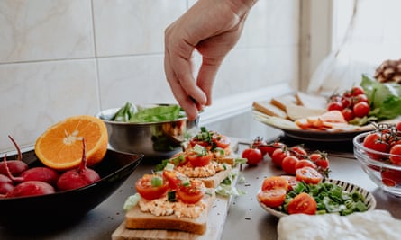 A hand seasoning a vegetarian bruschetta with basil and garlic
