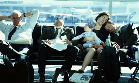 Travellers including a family and business people napping in an airport