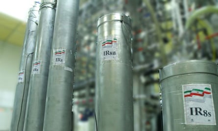 Close-up photo of a number of tall, thin metal cylinders bearing labels with the Iranian flag, inside an industrial facility