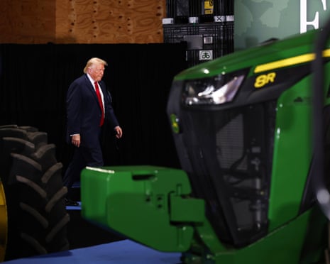 a man in suit walks near a green tractor