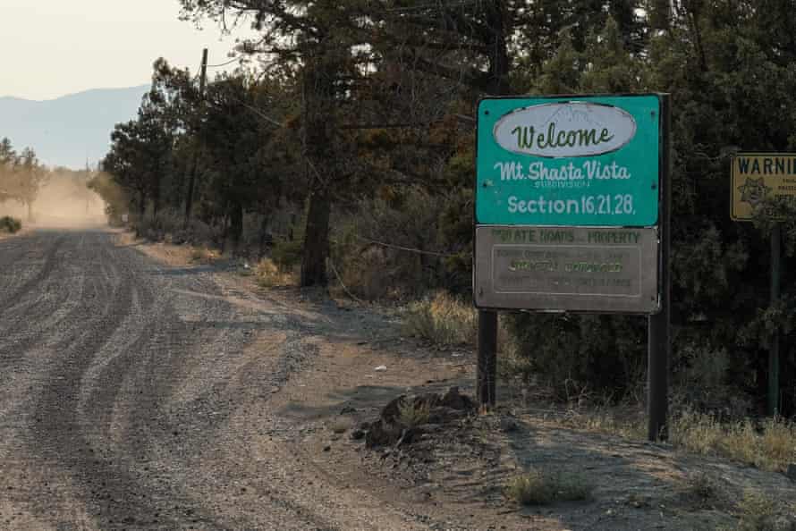 A green sign next to a dirt road reads 'Welcome, Mt Shasta Vista subdivision' in handpainted brush script.
