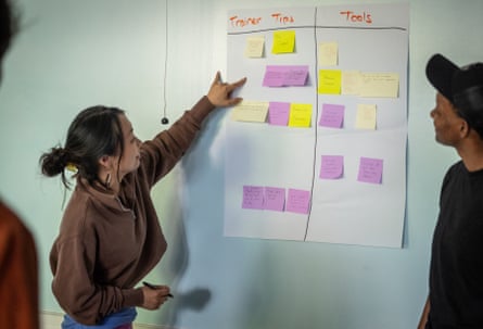A woman and two men looking at post it