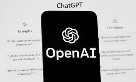 The OpenAI logo  on a mobile phone in front of a computer screen which displays the ChatGPT home screen.