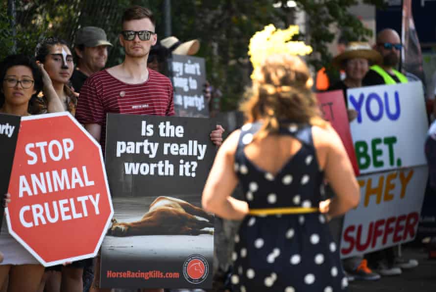 A racegoer walks past animal welfare activists on Melbourne Cup Day in 2019.