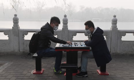Two men play Chinese chess beside a lake on a heavily polluted day in Beijing on 1 January.