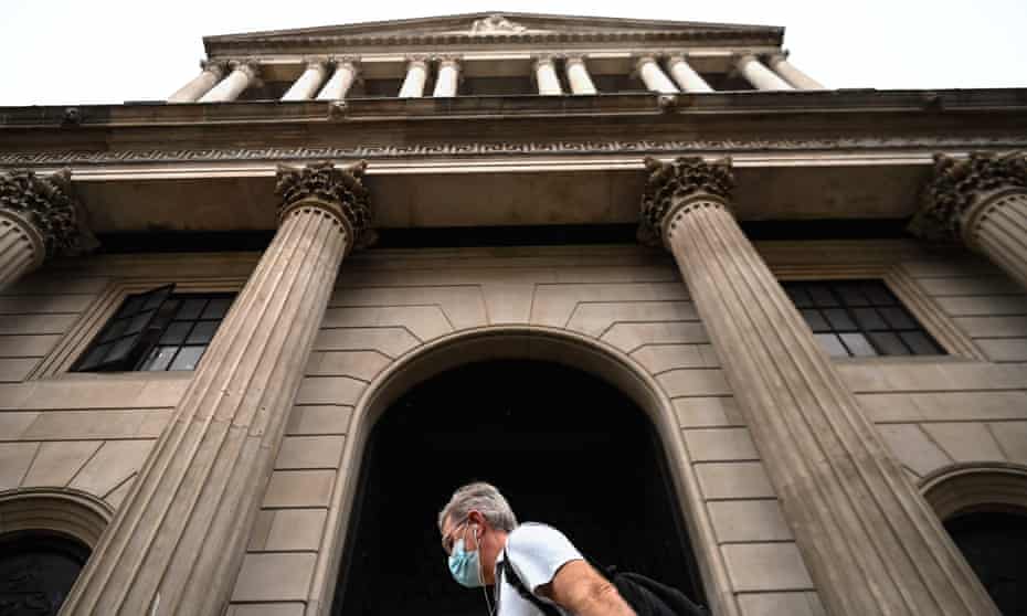 A man in a face mask walking past the Bank of England on Threadneedle Street.
