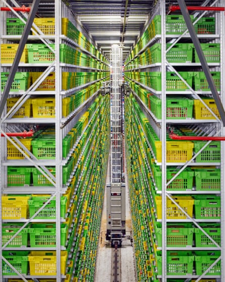 A robotic crane picks crates from towering shelves at an Ocado warehouse in Hatfield